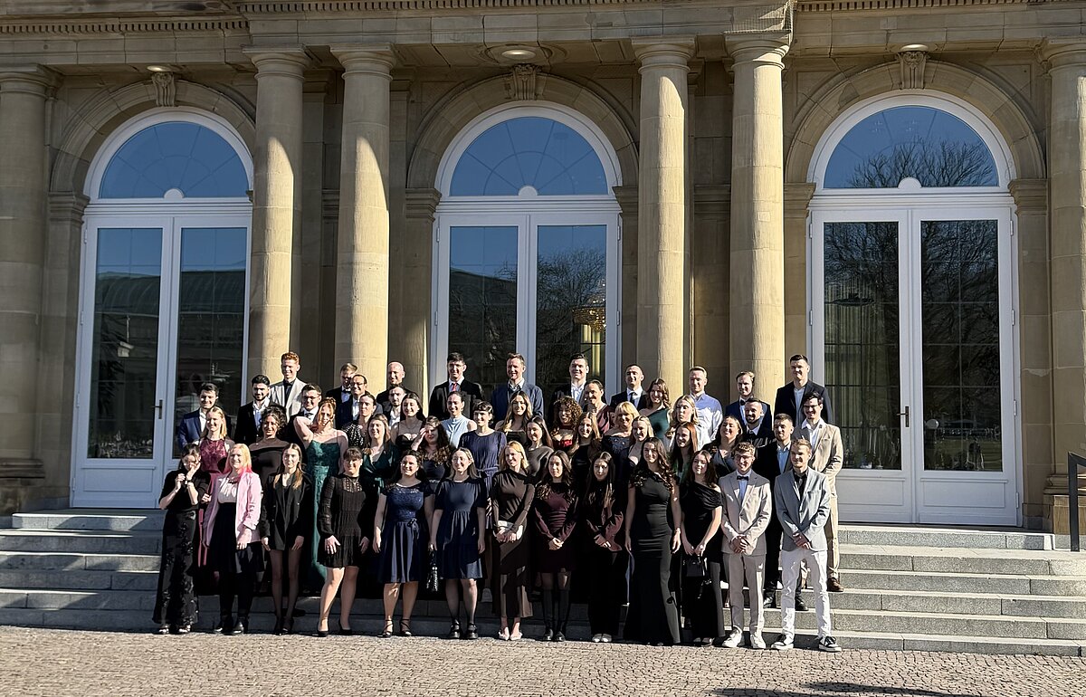 Gruppenfoto der Absolventen des Bachelorstudiengangs Steuerverwaltung Jahrgang 2023 vor dem Neuen Schloss in Stuttgart bei strahlendem Sonnenschein.