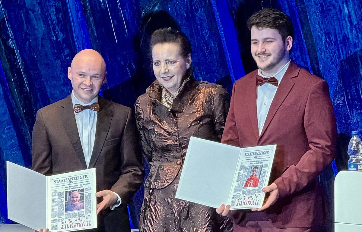 Breda Nußbaum verleiht den Preis für besonderes Engagement an Max Karrenführ und Simon Rehman bei der Bachelorfeier 2026 der Hochschule Ludwigsburg.