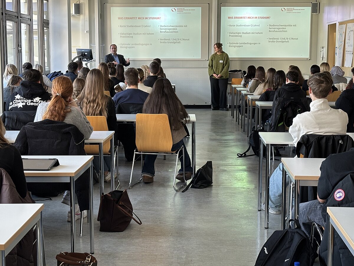 Dozent präsentiert den Studiengang Public Financial Management (PFM) vor vielen Studieninteressierten.