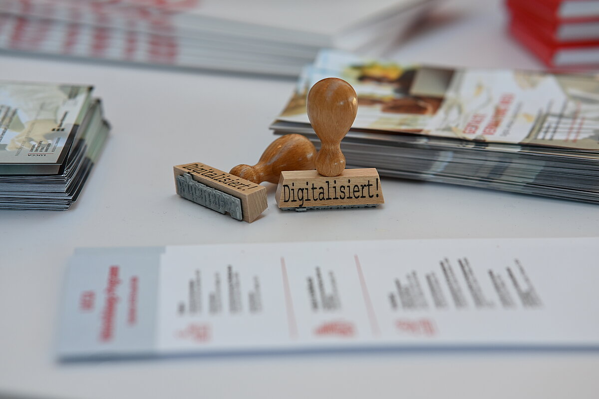 Holzstempel mit der Aufschrift "Digitalisiert!" als Symbol für die digitale Transformation auf der OZG-Taskforce Konferenz.