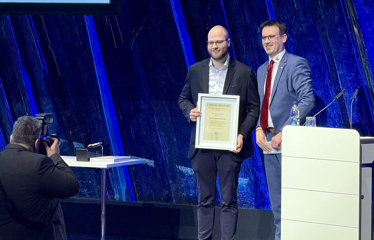 Michael Dambacher verleiht Pascal Kuhring den Preis des Gemeindetags für seine Bachelorarbeit bei der Bachelorfeier 2026 der Hochschule Ludwigsburg.