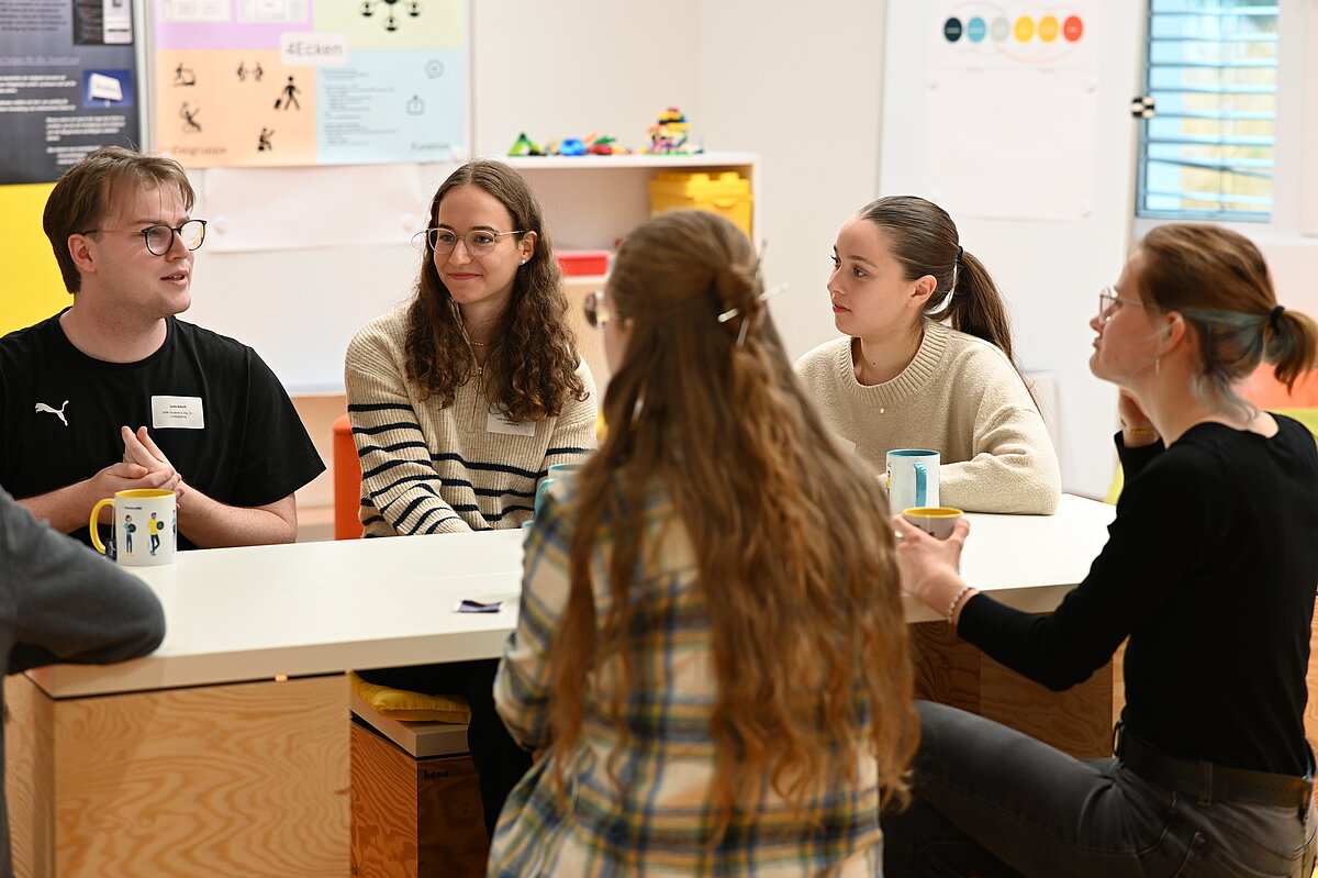 Zwei Studierende stellen ihre Projekte auf der DVM-Fachtagung vor, sitzend an einem Tisch im Austausch.