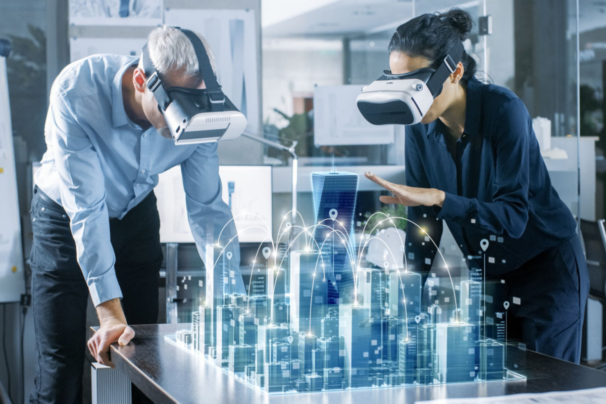 Zwei Personen mit VR-Headsets betrachten ein holografisches 3D-Stadtmodell auf einem Tisch, das eine vernetzte Smart City darstellt.